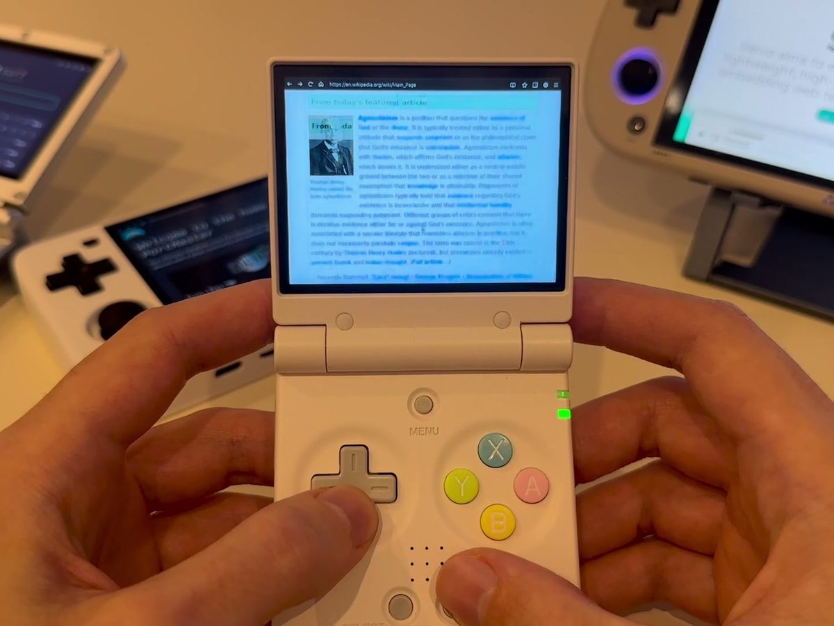 A Miyoo Mini Flip showing Wikipedia in retsurf, held in two hands